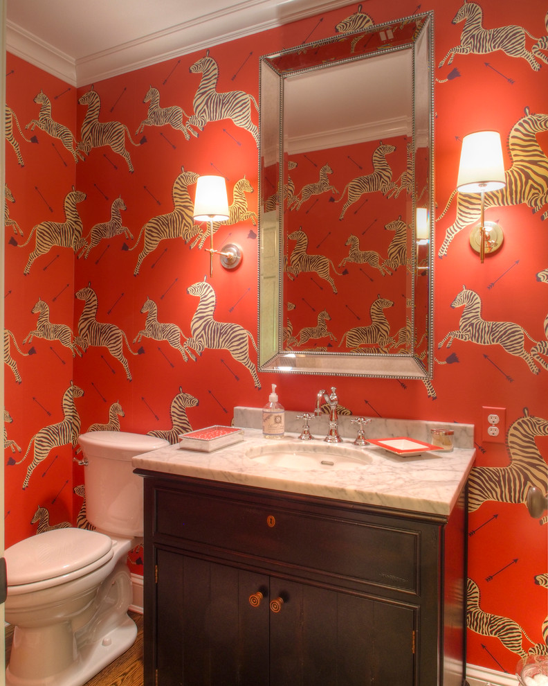 Small eclectic powder room in Philadelphia with an undermount sink, dark wood cabinets, marble benchtops, a two-piece toilet, beaded inset cabinets, medium hardwood floors, red walls and white benchtops.