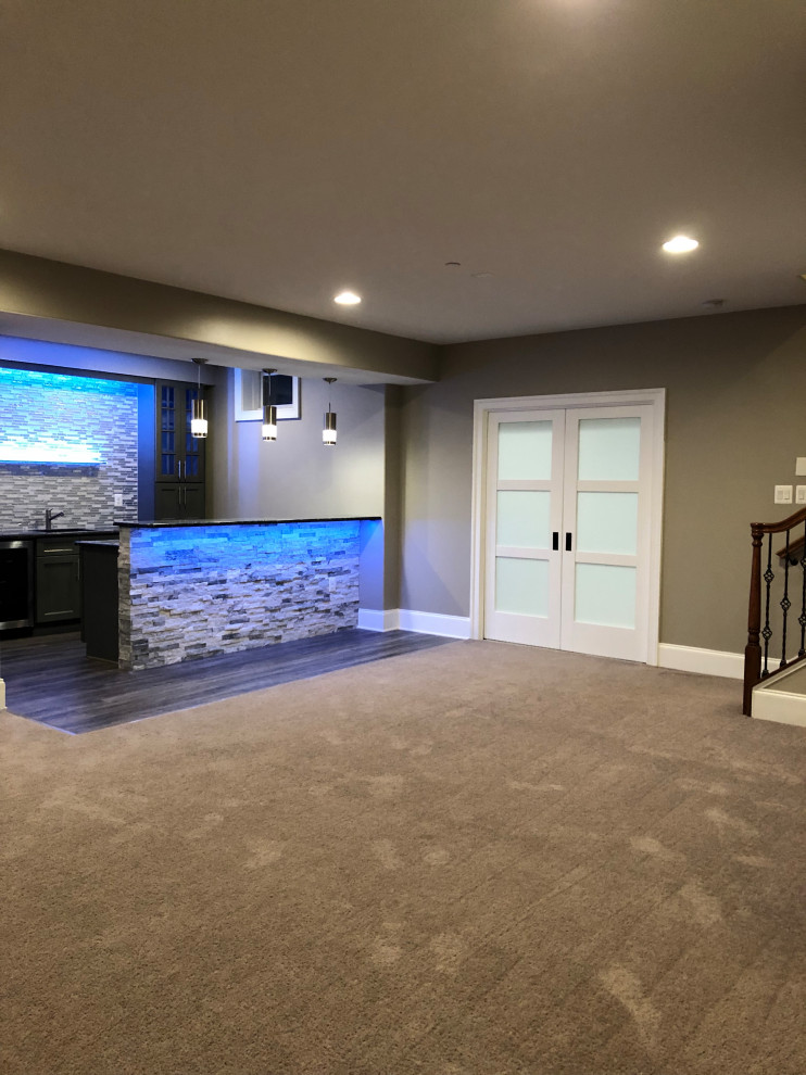 Inspiration for a large modern look-out basement with grey walls, carpet, a ribbon fireplace, a stone fireplace surround and beige floor.