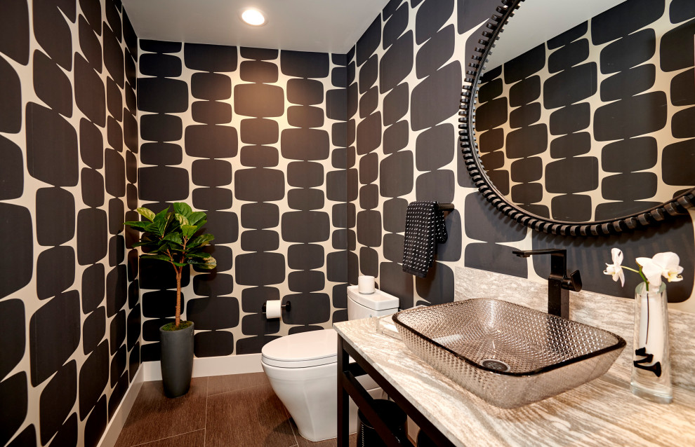 Photo of a medium sized contemporary cloakroom in Denver with black cabinets, a one-piece toilet, black walls, porcelain flooring, a vessel sink, travertine worktops, grey floors, white worktops, a freestanding vanity unit and wallpapered walls.