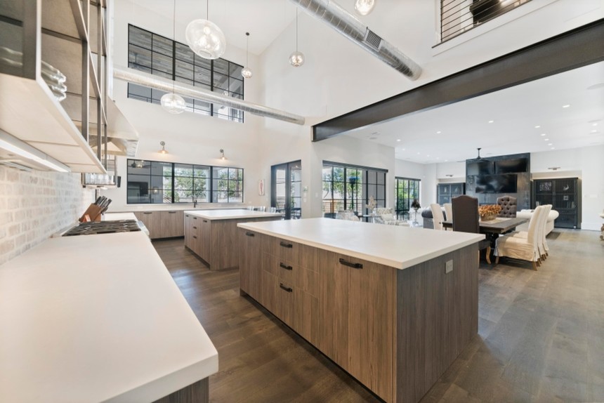 This is an example of a large industrial u-shaped open plan kitchen in Houston with an undermount sink, flat-panel cabinets, distressed cabinets, quartz benchtops, multi-coloured splashback, stone tile splashback, stainless steel appliances, painted wood floors, multiple islands, brown floor and grey benchtop.