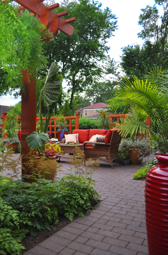Photo of a small eclectic backyard patio in Chicago with brick pavers and a pergola.