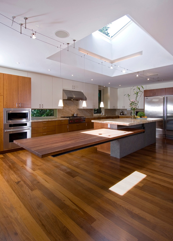 This is an example of a contemporary kitchen in Toronto with stainless steel appliances, wood benchtops, flat-panel cabinets and medium wood cabinets.