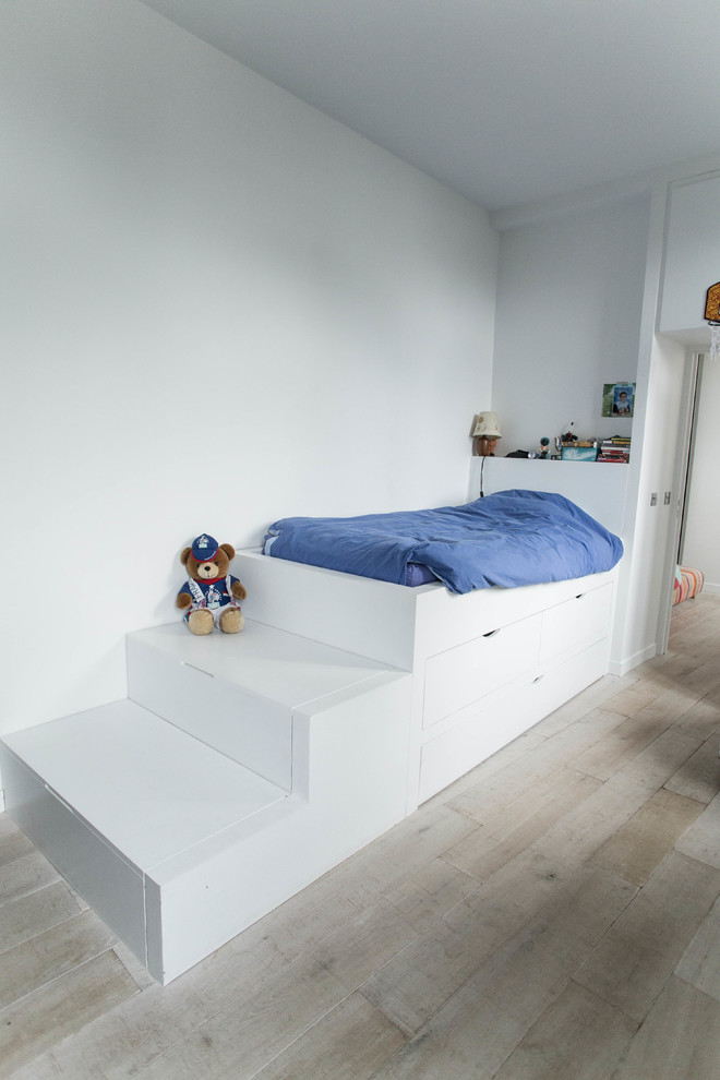 This is an example of a mid-sized contemporary kids' bedroom for kids 4-10 years old and boys in Paris with blue walls, light hardwood floors and beige floor.