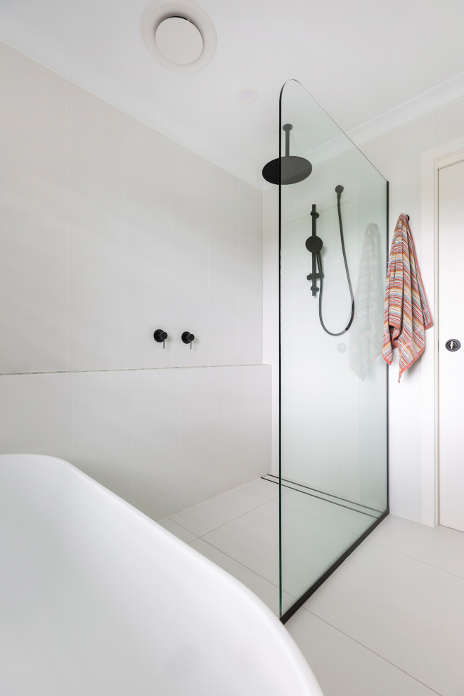 Стильный дизайн: главная ванная комната среднего размера в современном стиле с фасадами островного типа, отдельно стоящей ванной, унитазом-моноблоком, белой плиткой, керамической плиткой, белыми стенами, белым полом, открытым душем и подвесной тумбой - последний тренд