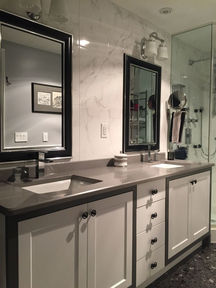 Example of a large transitional master white tile and stone tile gray floor corner shower design in Toronto with shaker cabinets, white cabinets, white walls, an undermount sink, quartz countertops and a hinged shower door