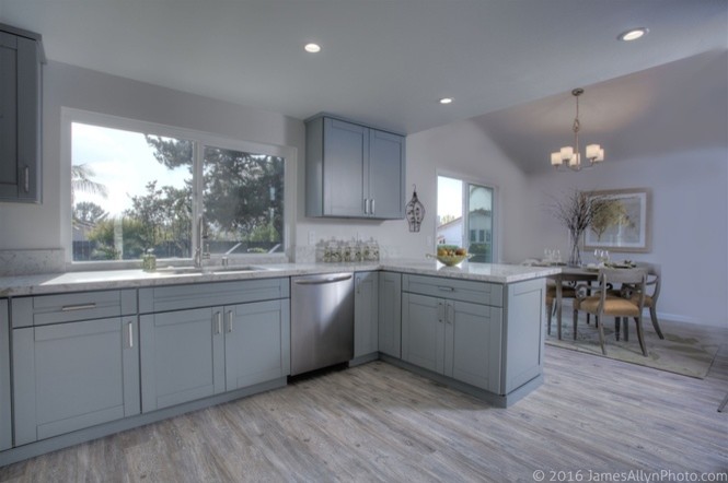 Inspiration for a mid-sized beach style u-shaped eat-in kitchen in San Diego with shaker cabinets, stainless steel appliances, laminate floors, a peninsula and grey floor.