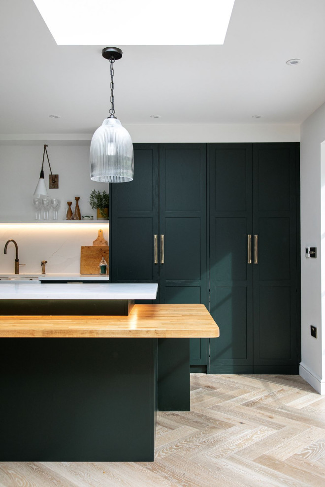 This is an example of a contemporary l-shaped open plan kitchen in Other with shaker cabinets, green cabinets, quartz worktops, white splashback, engineered quartz splashback, integrated appliances, an island and white worktops.