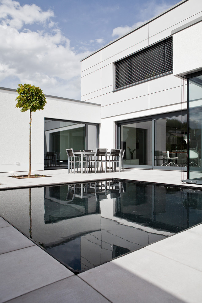 Kleiner Moderner Pool hinter dem Haus in rechteckiger Form mit Betonboden in Sonstige
