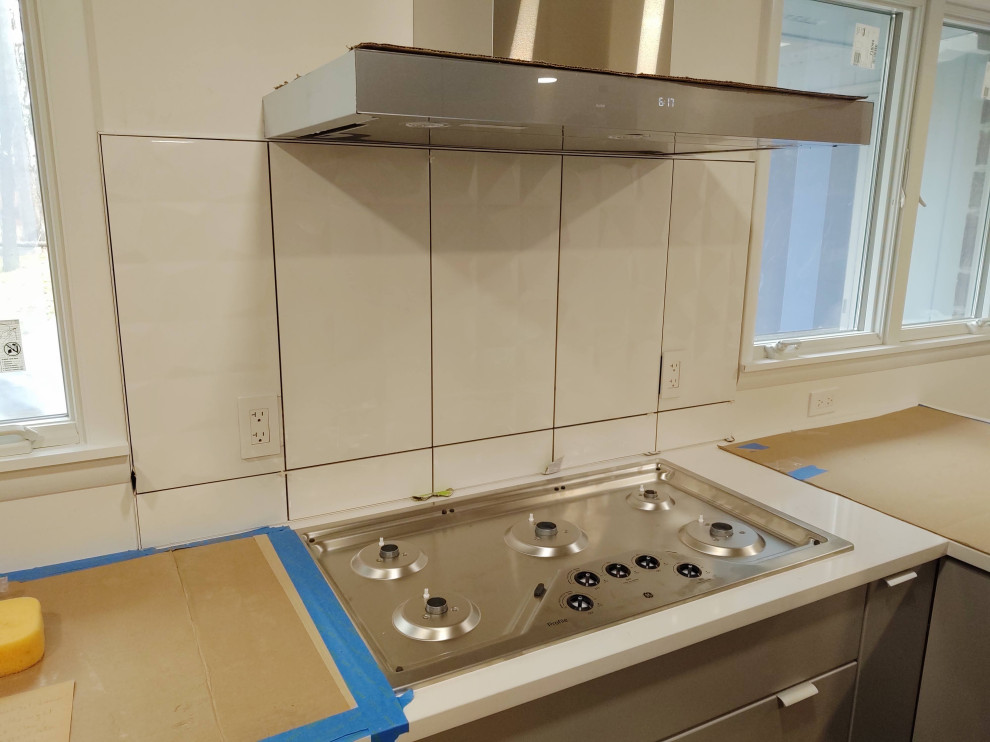 Inspiration for a mid-sized enclosed kitchen remodel with flat-panel cabinets, gray cabinets and a peninsula