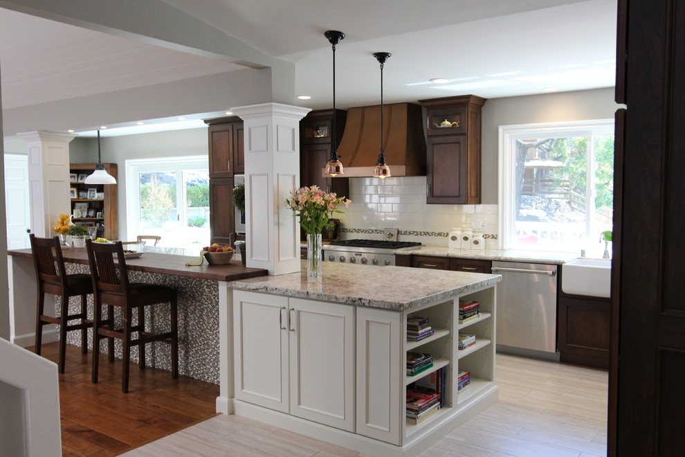 Eat-in kitchen - mid-sized rustic l-shaped porcelain tile eat-in kitchen idea in San Francisco with a farmhouse sink, recessed-panel cabinets, dark wood cabinets, wood countertops, white backsplash, subway tile backsplash, paneled appliances and an island