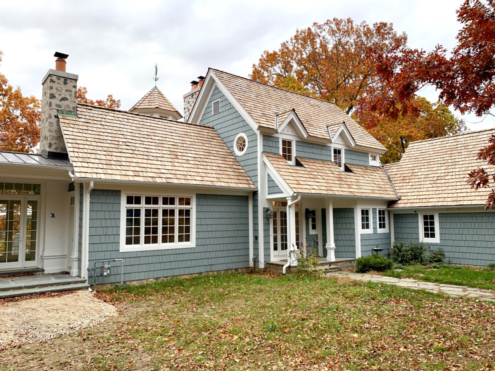 This is an example of an expansive traditional two-storey blue house exterior in Milwaukee with wood siding, a gable roof, a shingle roof, a brown roof and shingle siding.
