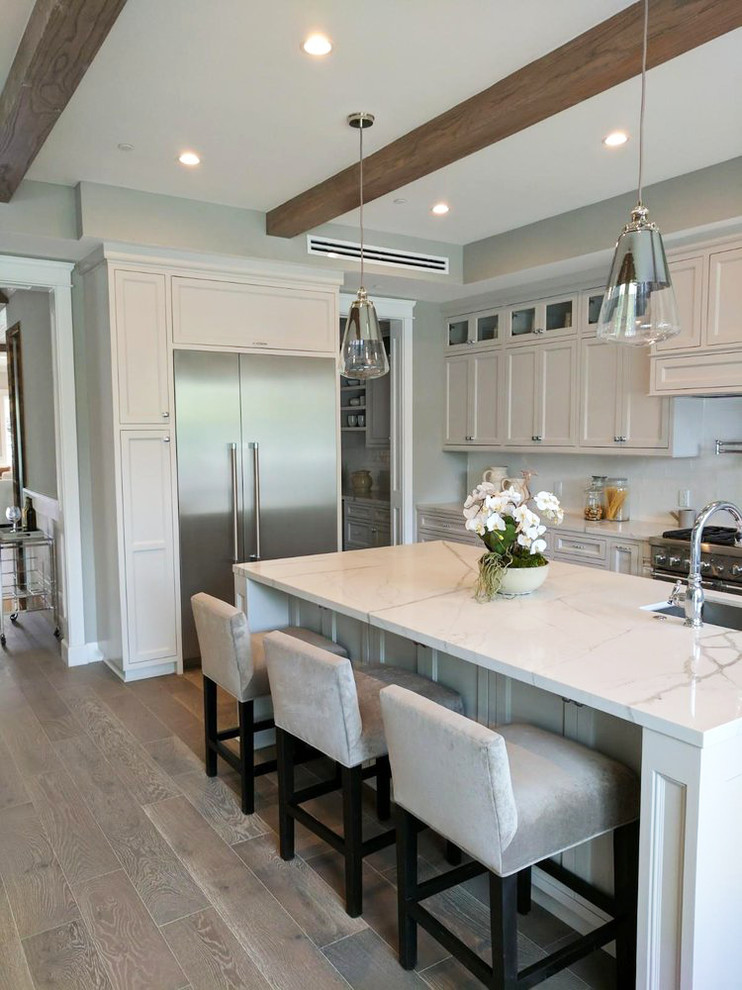 Large modern u-shaped eat-in kitchen in San Francisco with an integrated sink, louvered cabinets, white cabinets, marble benchtops, white splashback, stainless steel appliances, light hardwood floors, with island, grey floor, white benchtop and porcelain splashback.