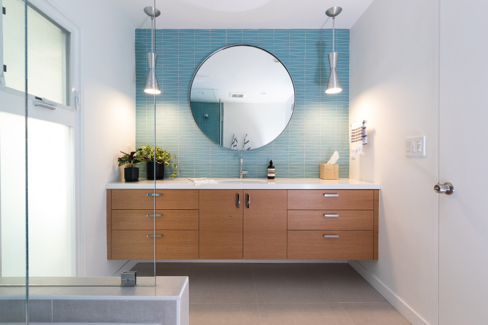 Стильный дизайн: главная ванная комната среднего размера в стиле ретро с плоскими фасадами, коричневыми фасадами, накладной ванной, угловым душем, унитазом-моноблоком, синей плиткой, стеклянной плиткой, белыми стенами, полом из керамической плитки, врезной раковиной, столешницей из искусственного кварца, бежевым полом, душем с распашными дверями, белой столешницей, тумбой под одну раковину и подвесной тумбой - последний тренд