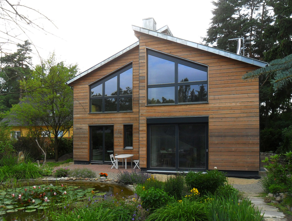 Mid-sized country two-storey brown exterior in Berlin with wood siding and a shed roof.