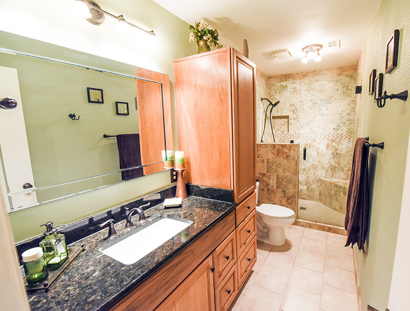 Photo of a contemporary bathroom in Phoenix with raised-panel cabinets, medium wood cabinets, an alcove shower, beige tile, green walls, porcelain floors, an undermount sink, granite benchtops and a two-piece toilet.