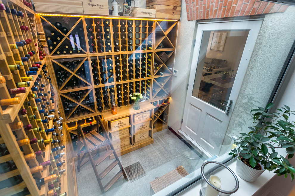 Design ideas for a mid-sized modern wine cellar in London with storage racks and grey floor.
