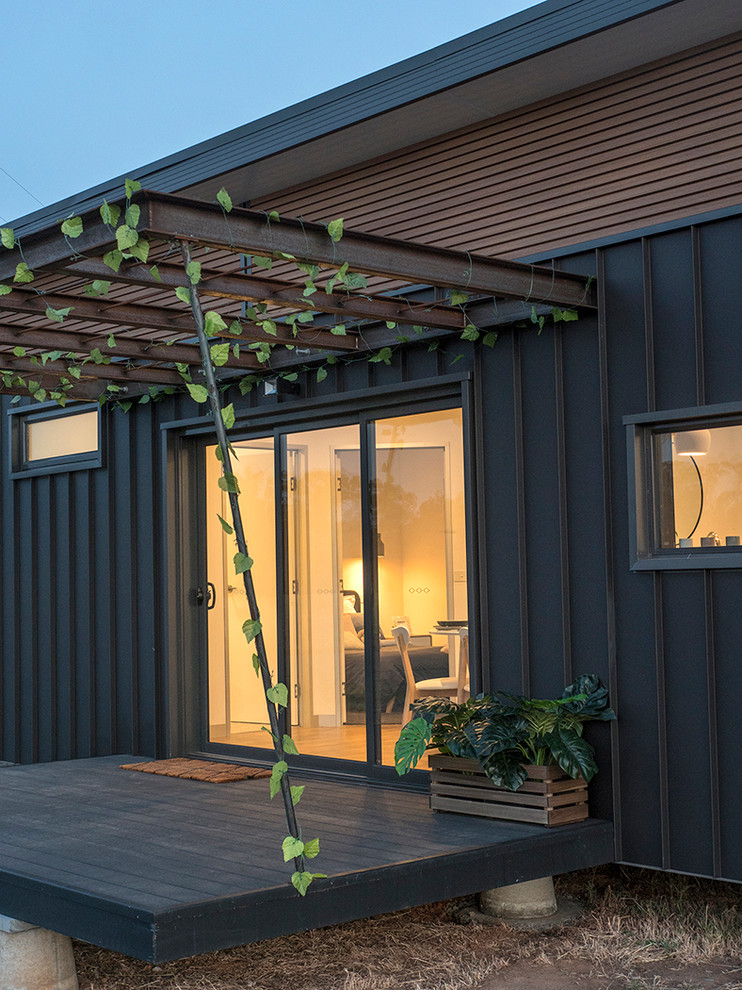 Small contemporary one-storey black house exterior in Other with metal siding and a metal roof.