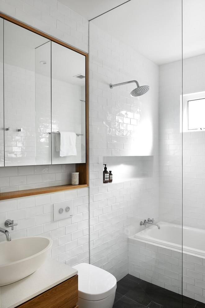 Photo of a contemporary 3/4 bathroom in Sydney with flat-panel cabinets, medium wood cabinets, a drop-in tub, a curbless shower, white tile, subway tile, white walls, a vessel sink, grey floor, an open shower and white benchtops.