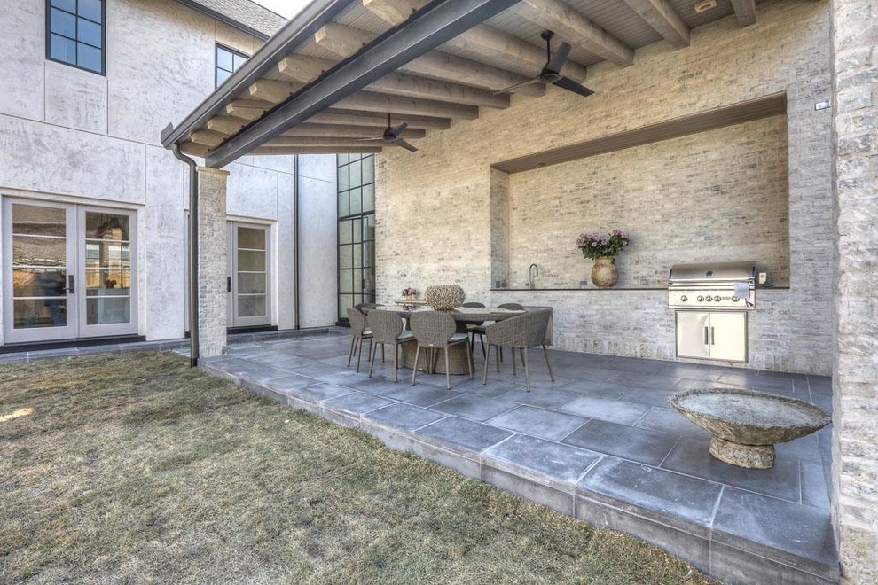Photo of a mid-sized transitional backyard patio in Houston with an outdoor kitchen, concrete pavers and a roof extension.