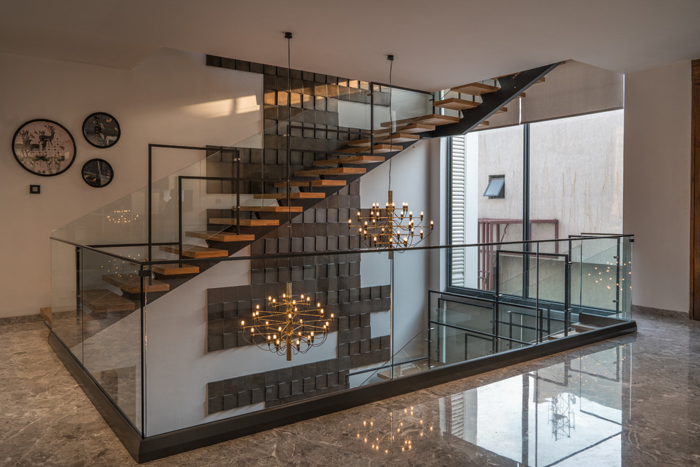 Inspiration for a contemporary wood l-shaped staircase in Hyderabad with open risers and glass railing.