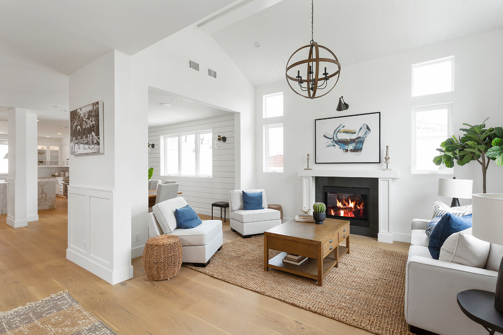 Photo of a transitional formal open concept living room in Los Angeles with white walls, medium hardwood floors, a standard fireplace, no tv and brown floor.