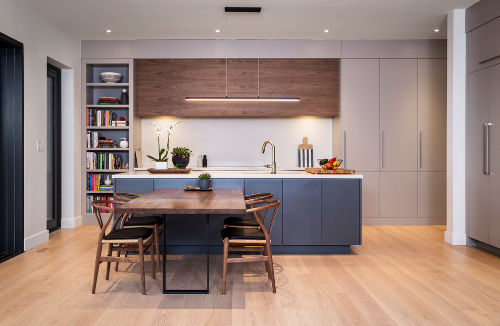 This is an example of a large contemporary galley kitchen in Toronto with flat-panel cabinets, grey cabinets, light hardwood floors, with island, beige floor and white benchtop.