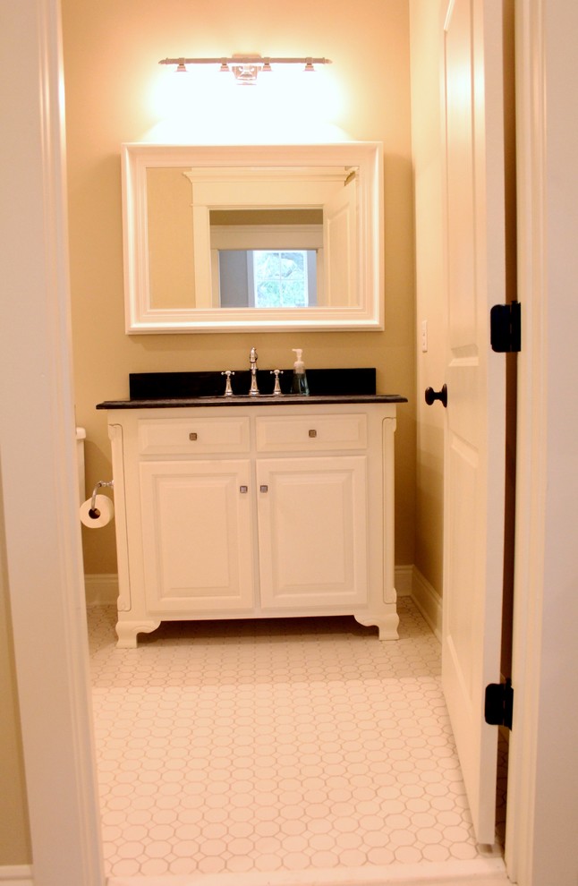 Photo of a kids bathroom in Other with an undermount sink, raised-panel cabinets, white cabinets, granite benchtops, a drop-in tub, a shower/bathtub combo, a one-piece toilet, white tile, beige walls and ceramic floors.