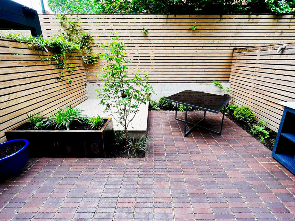 Cette image montre une petite terrasse design avec une cour et des pavés en pierre naturelle.