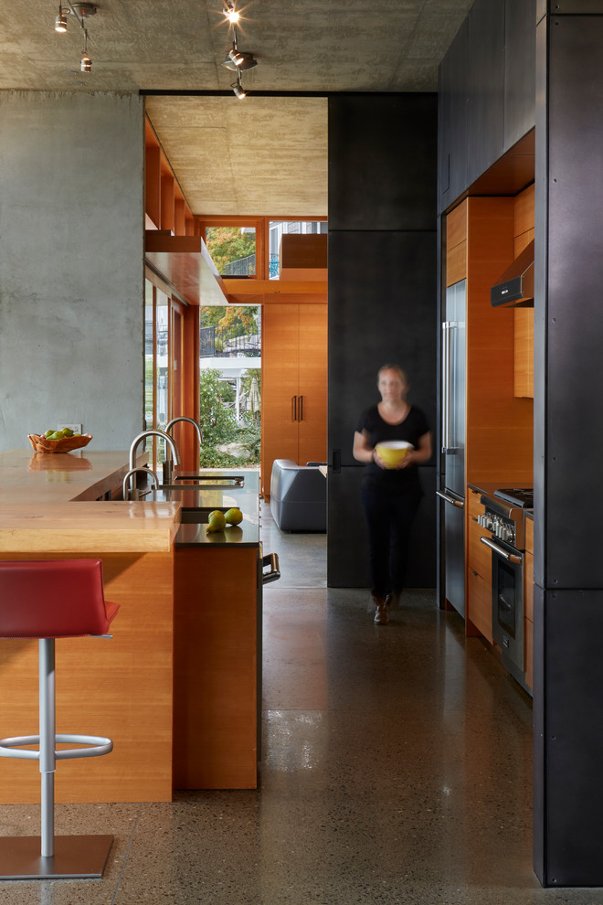 Photo of a contemporary galley kitchen in Seattle with flat-panel cabinets, medium wood cabinets, stainless steel appliances and with island.