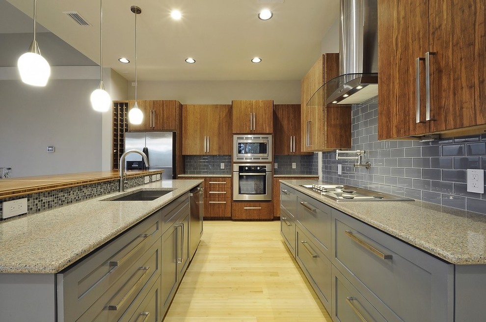 Design ideas for a contemporary kitchen in Austin with an undermount sink, flat-panel cabinets, medium wood cabinets, grey splashback, subway tile splashback and stainless steel appliances.