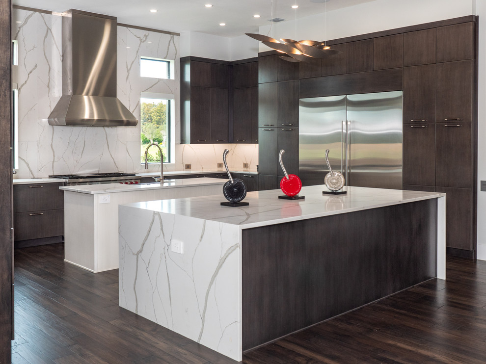 Inspiration for a contemporary u-shaped dark wood floor and brown floor kitchen remodel in Tampa with flat-panel cabinets, dark wood cabinets, white backsplash, stone slab backsplash, stainless steel appliances, two islands and white countertops