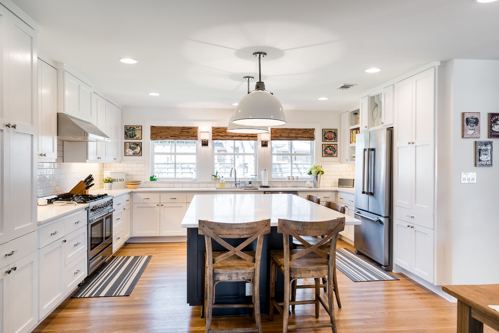 Design ideas for a large transitional u-shaped eat-in kitchen in Austin with a double-bowl sink, recessed-panel cabinets, white cabinets, quartz benchtops, white splashback, subway tile splashback, stainless steel appliances, medium hardwood floors and with island.
