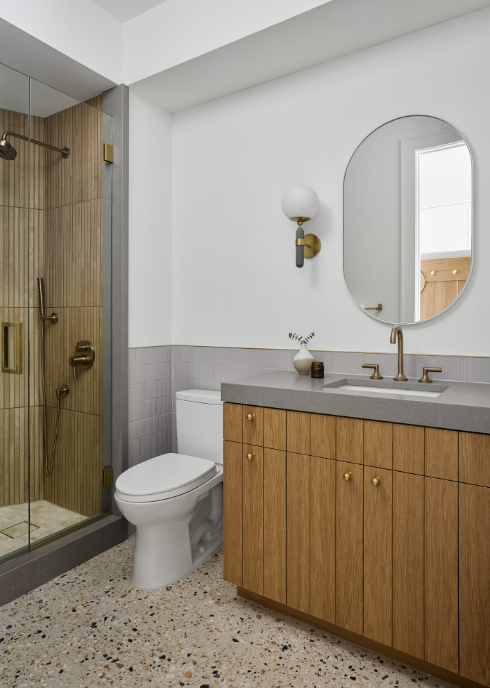 Foto på ett mellanstort funkis grå badrum, med skåp i ljust trä, en hörndusch, vit kakel, keramikplattor, vita väggar, klinkergolv i keramik, bänkskiva i kvarts, flerfärgat golv och dusch med gångjärnsdörr