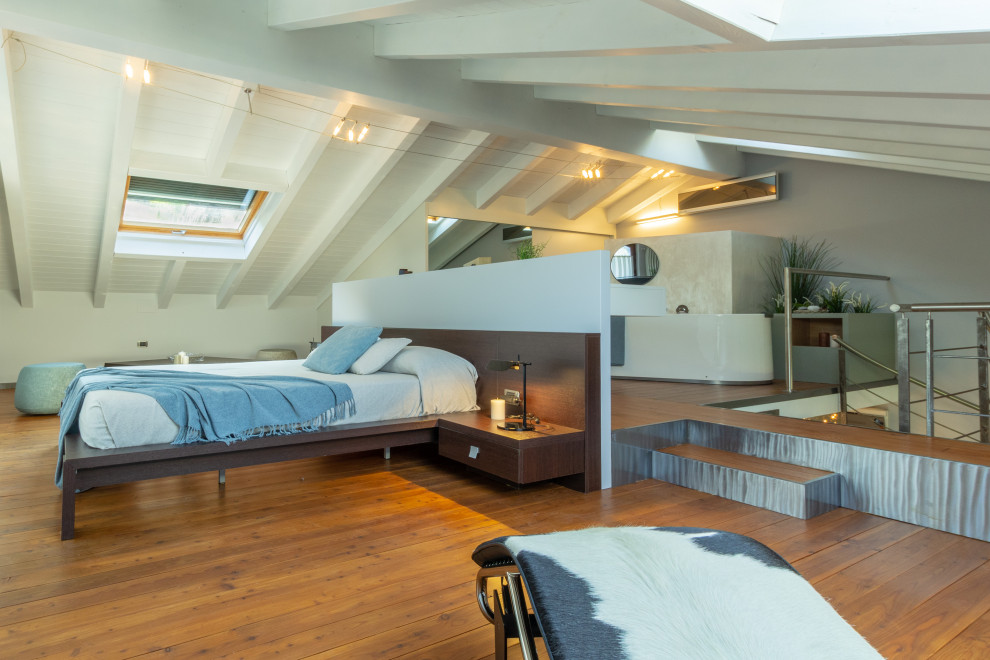 Photo of an expansive contemporary loft-style bedroom in Other with blue walls, painted wood floors and brown floor.