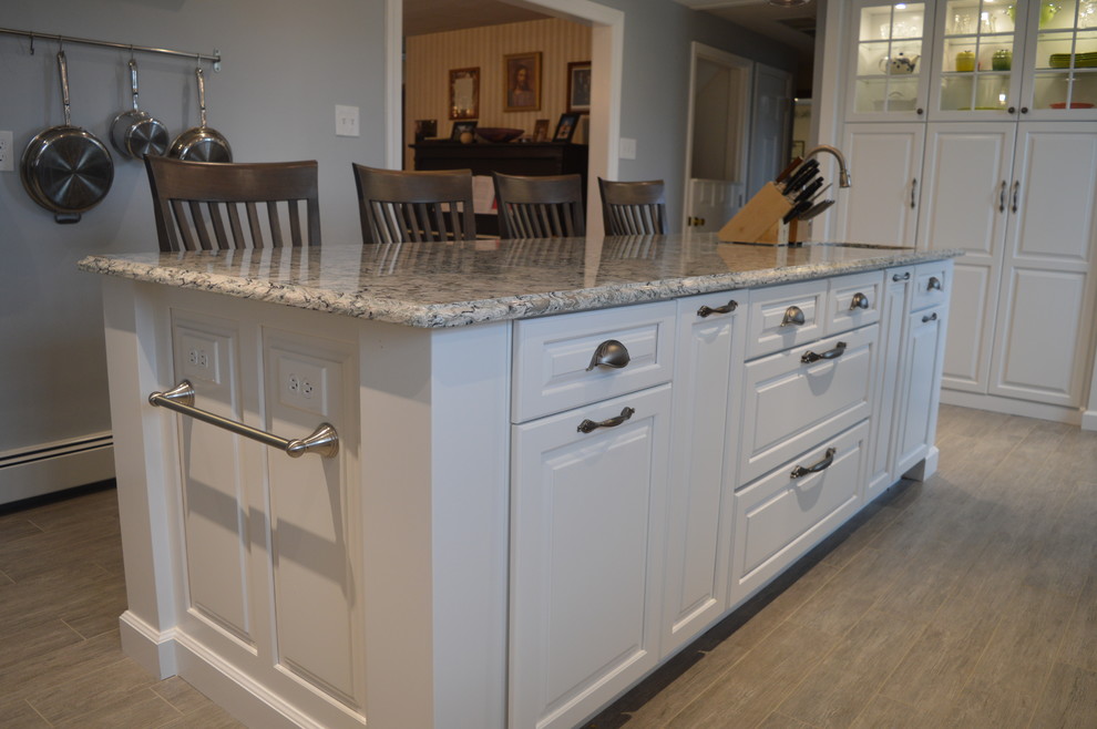 Inspiration for a large transitional u-shaped ceramic tile and gray floor enclosed kitchen remodel with a farmhouse sink, raised-panel cabinets, white cabinets, quartz countertops, gray backsplash, glass tile backsplash, stainless steel appliances and an island