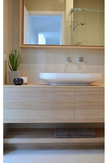 Design ideas for a contemporary bathroom in Melbourne with flat-panel cabinets, light wood cabinets, a corner shower, porcelain tile, beige walls, porcelain floors, a vessel sink, laminate benchtops, beige floor and a hinged shower door.