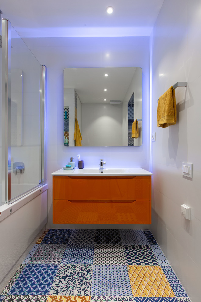 Design ideas for a large contemporary kids bathroom in Other with furniture-like cabinets, orange cabinets, a corner tub, a corner shower, a wall-mount toilet, white tile, ceramic tile, white walls, ceramic floors, an integrated sink, solid surface benchtops, multi-coloured floor, a hinged shower door and white benchtops.