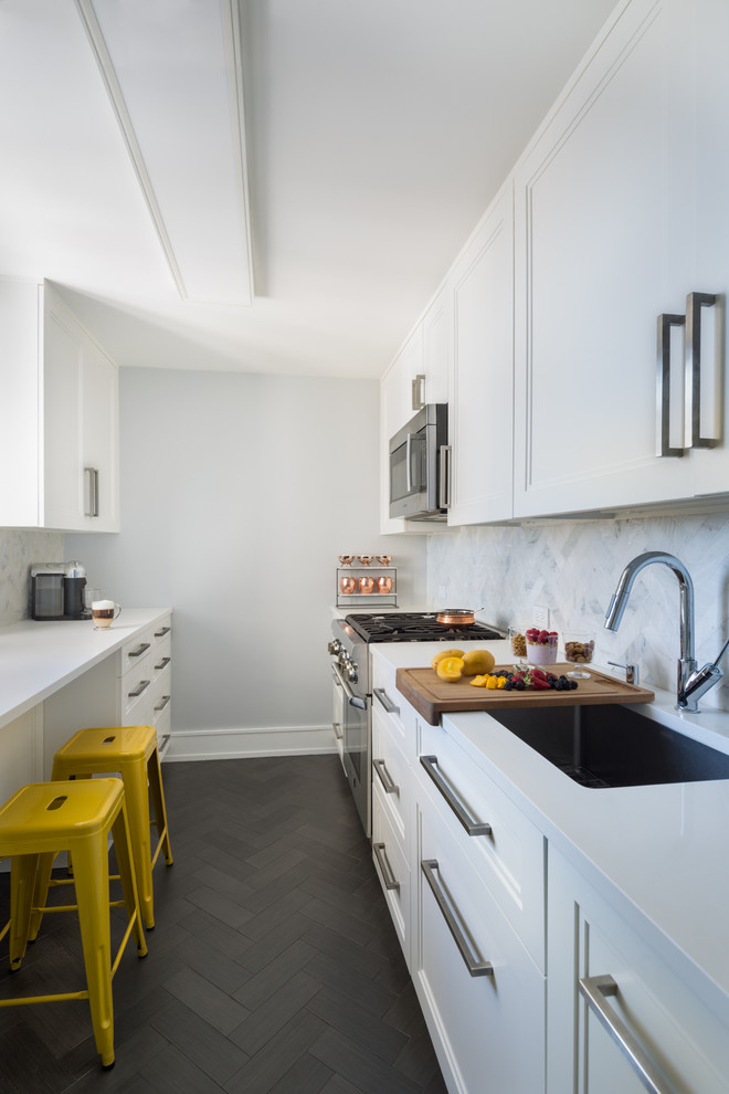 This is an example of a mid-sized contemporary galley separate kitchen in New York with an undermount sink, shaker cabinets, white cabinets, quartz benchtops, white splashback, marble splashback, panelled appliances, porcelain floors, no island, grey floor and white benchtop.