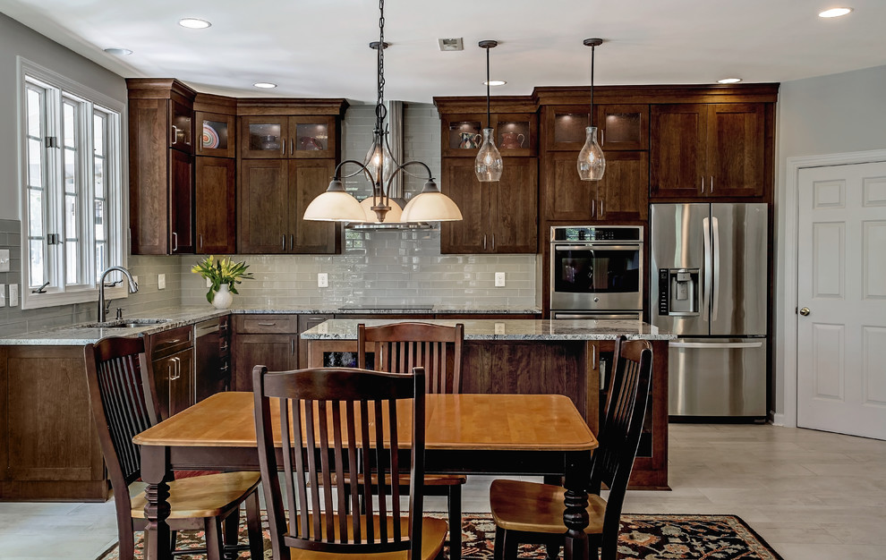 Example of a mid-sized transitional l-shaped porcelain tile and beige floor open concept kitchen design in DC Metro with an undermount sink, glass-front cabinets, dark wood cabinets, granite countertops, white backsplash, porcelain backsplash, stainless steel appliances, an island and white countertops