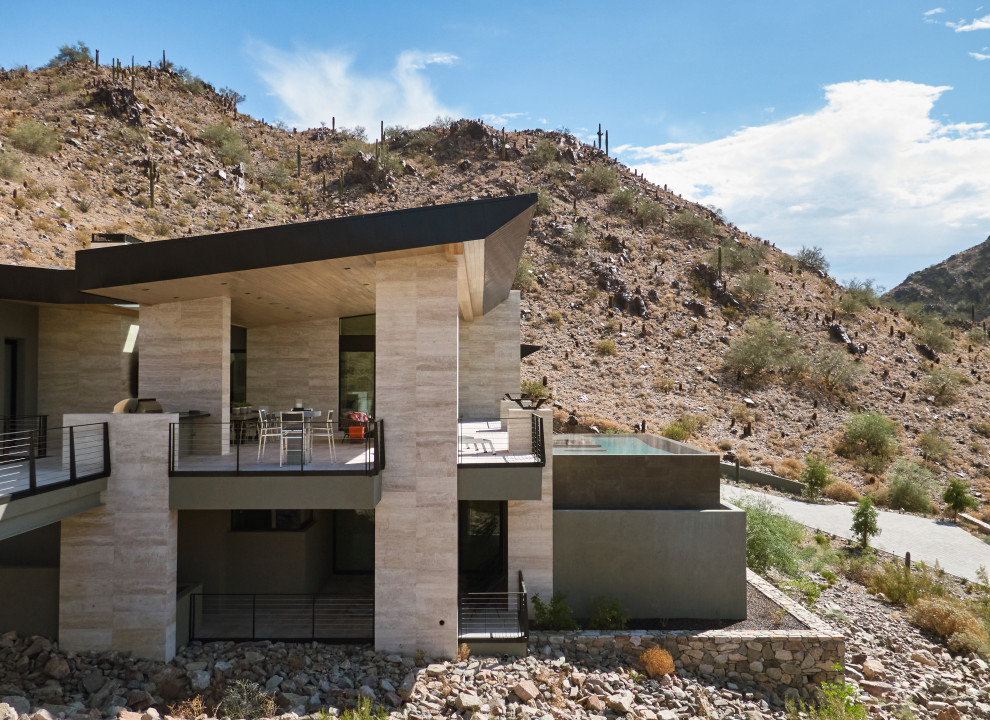 Expansive modern two-storey beige house exterior in Phoenix with stone veneer and a butterfly roof.