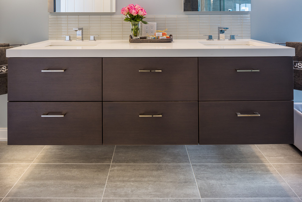 Large modern master bathroom in New York with an undermount sink, flat-panel cabinets, dark wood cabinets, engineered quartz benchtops, a drop-in tub, a one-piece toilet, gray tile, porcelain tile, blue walls and porcelain floors.