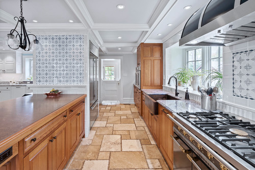 Transitional kitchen with light grey shaker kitchen cabinets, a large white quartz island, and a distinctive geometric-patterned backsplash.