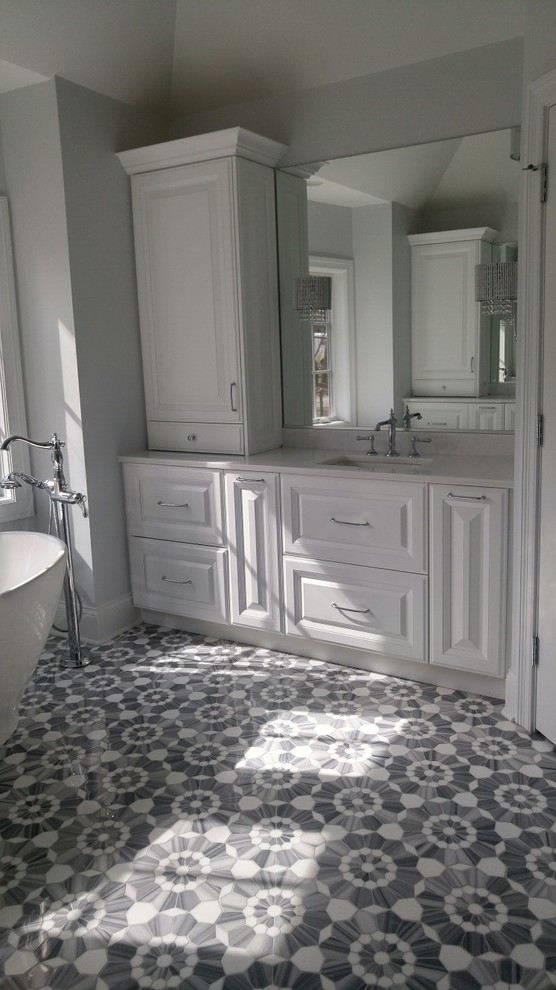 Lantlig inredning av ett stort vit vitt badrum, med luckor med upphöjd panel, vita skåp, ett fristående badkar, en kantlös dusch, en toalettstol med separat cisternkåpa, vit kakel, keramikplattor, blå väggar, marmorgolv, ett undermonterad handfat, marmorbänkskiva, blått golv och dusch med gångjärnsdörr