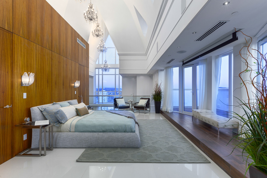 This is an example of a large contemporary master bedroom in Los Angeles with white walls, dark hardwood floors, no fireplace and brown floor.