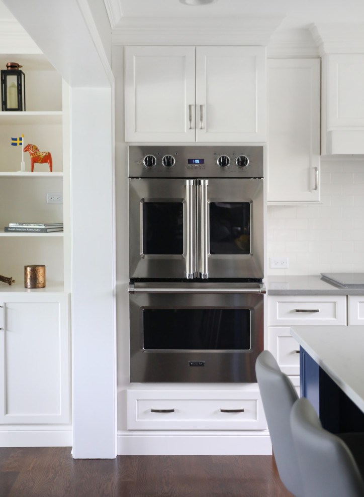 Example of a huge transitional dark wood floor and brown floor eat-in kitchen design in Chicago with shaker cabinets, white cabinets, white backsplash, porcelain backsplash, stainless steel appliances and white countertops