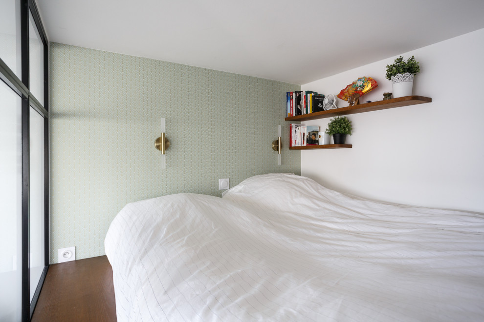Diseño de dormitorio tipo loft pequeño sin chimenea con paredes blancas, suelo de madera en tonos medios, suelo marrón y papel pintado
