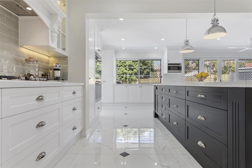 Photo of a large country galley eat-in kitchen in Brisbane with a farmhouse sink, white cabinets, marble benchtops, beige splashback, ceramic splashback, stainless steel appliances, ceramic floors, with island and white floor.