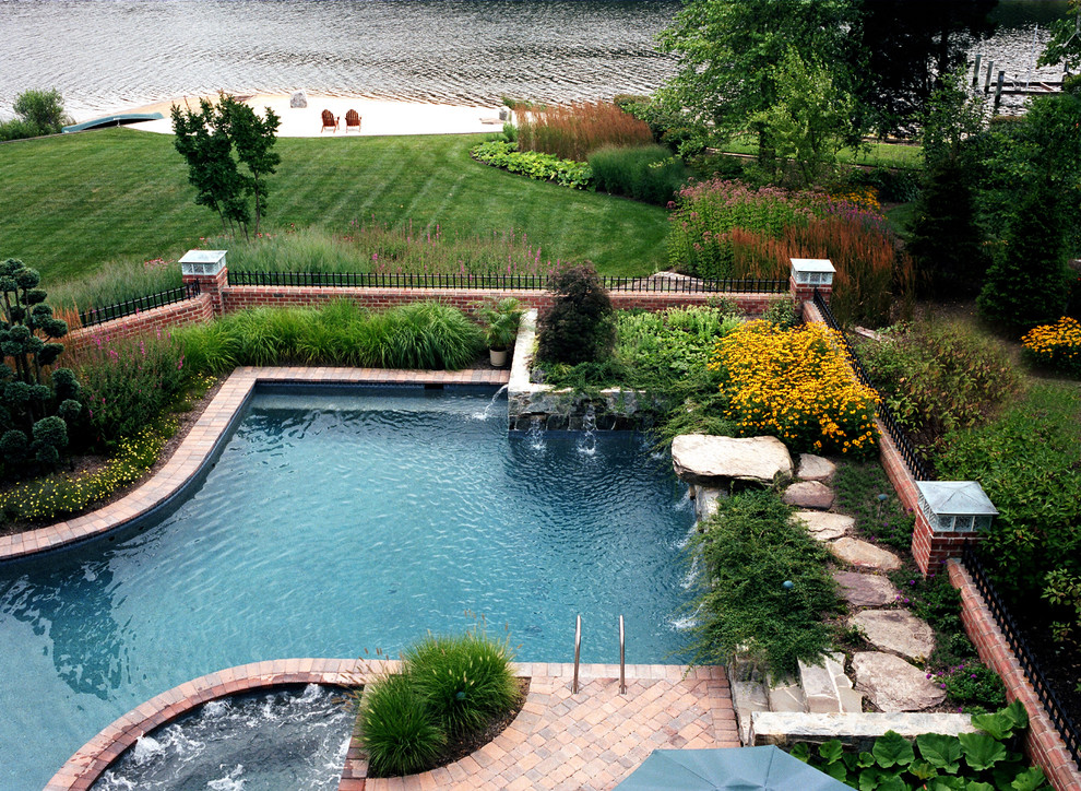 This is an example of a traditional pool in Baltimore with brick pavers and a water feature.