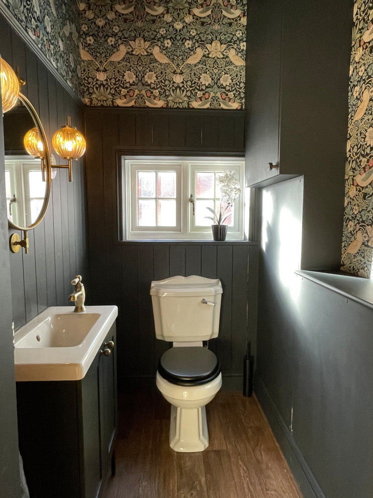 Klassische Gästetoilette mit Schrankfronten im Shaker-Stil, blauen Schränken, Toilette mit Aufsatzspülkasten, blauer Wandfarbe, Linoleum, braunem Boden, freistehendem Waschtisch und Wandpaneelen