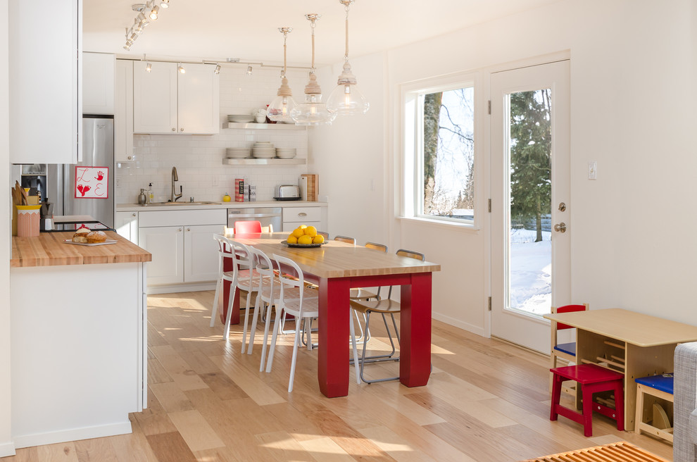 Inspiration for a mid-sized transitional l-shaped eat-in kitchen in Other with recessed-panel cabinets, white cabinets, wood benchtops, white splashback, subway tile splashback, light hardwood floors, no island, a drop-in sink and stainless steel appliances.